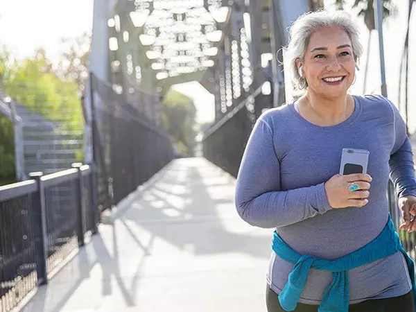 older woman smiling while jogging outside