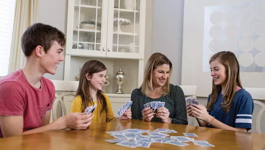 Young teenage family playing cards at a table.