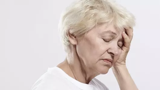 older woman holding head with hand