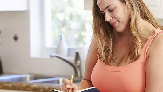 Woman logging calorie count in notebook