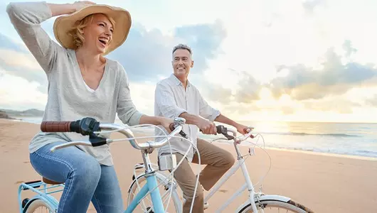 man and woman riding bikes on beach