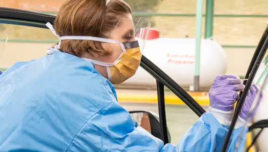 Woman in mask and scrubs with swab