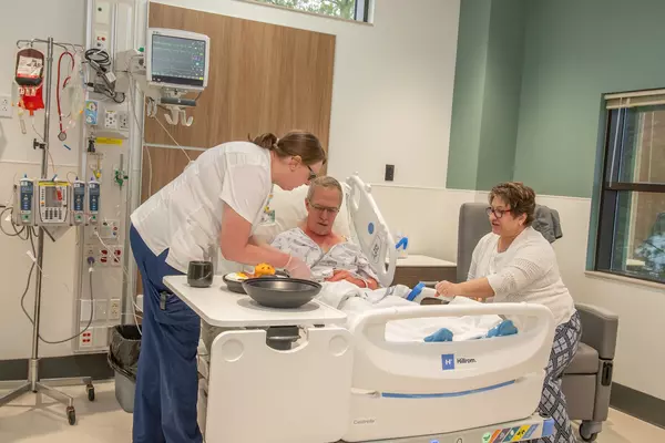 Nurse helping patient in hospital room training center.