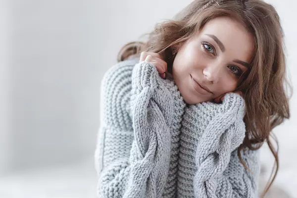 woman with a slight smile wearing a gray cozy sweater