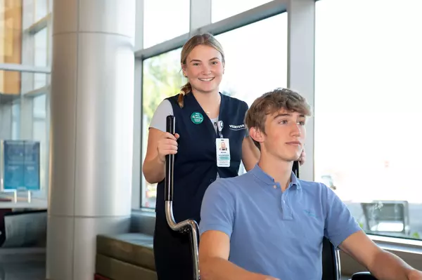 Gundersen volunteer pushing patient in wheelchair.