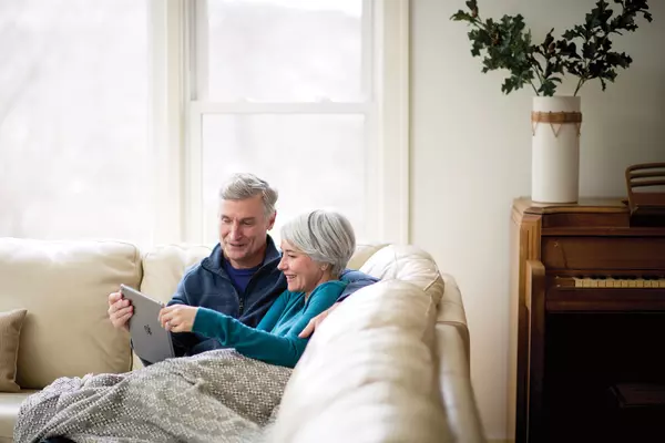 Senior couple looking at a tablet while sitting on the couch.